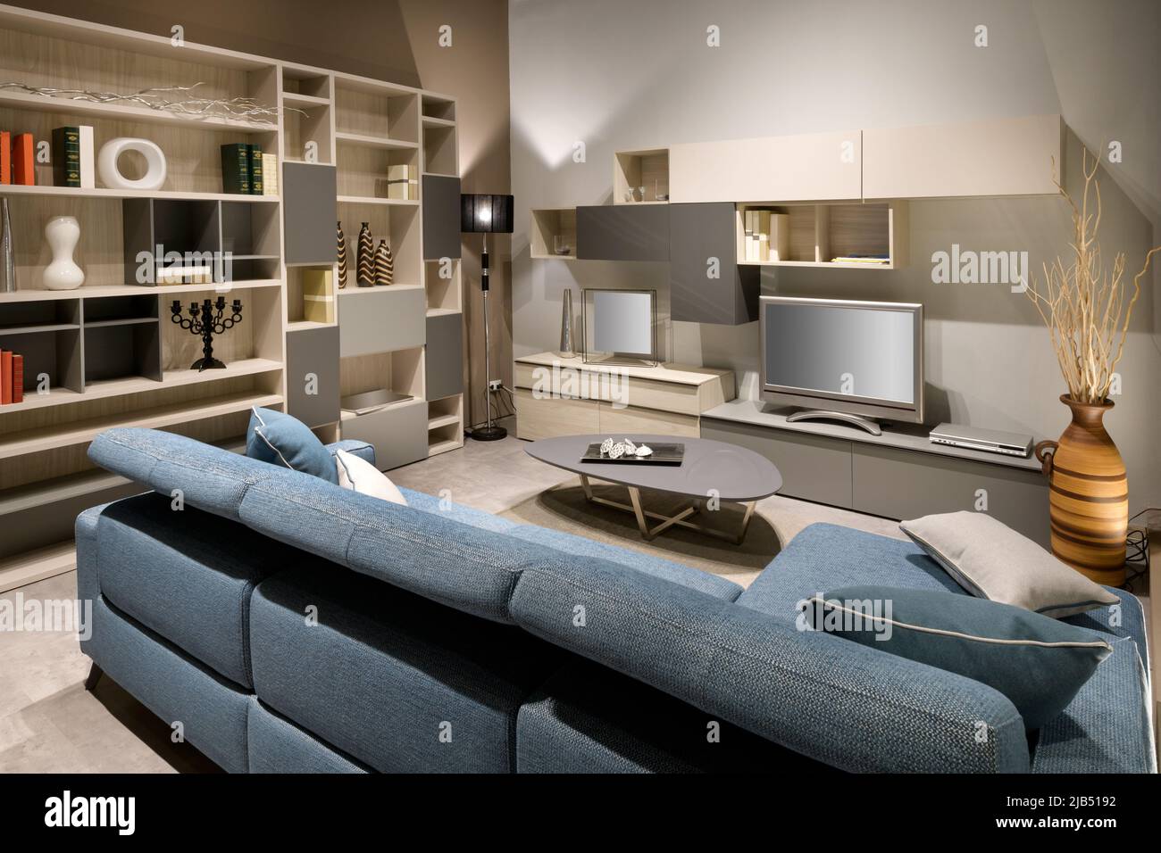 Comfortable sofa located near shelves with decorations and TV in modern