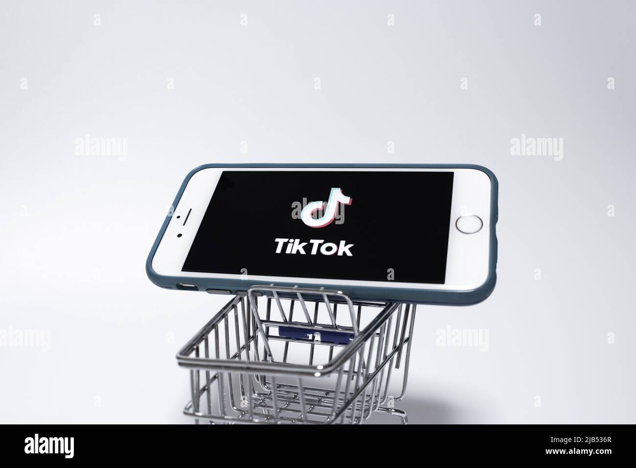 TikTok Logo on iPhone in miniaturae shopping cart. TikTok is a Chinese
