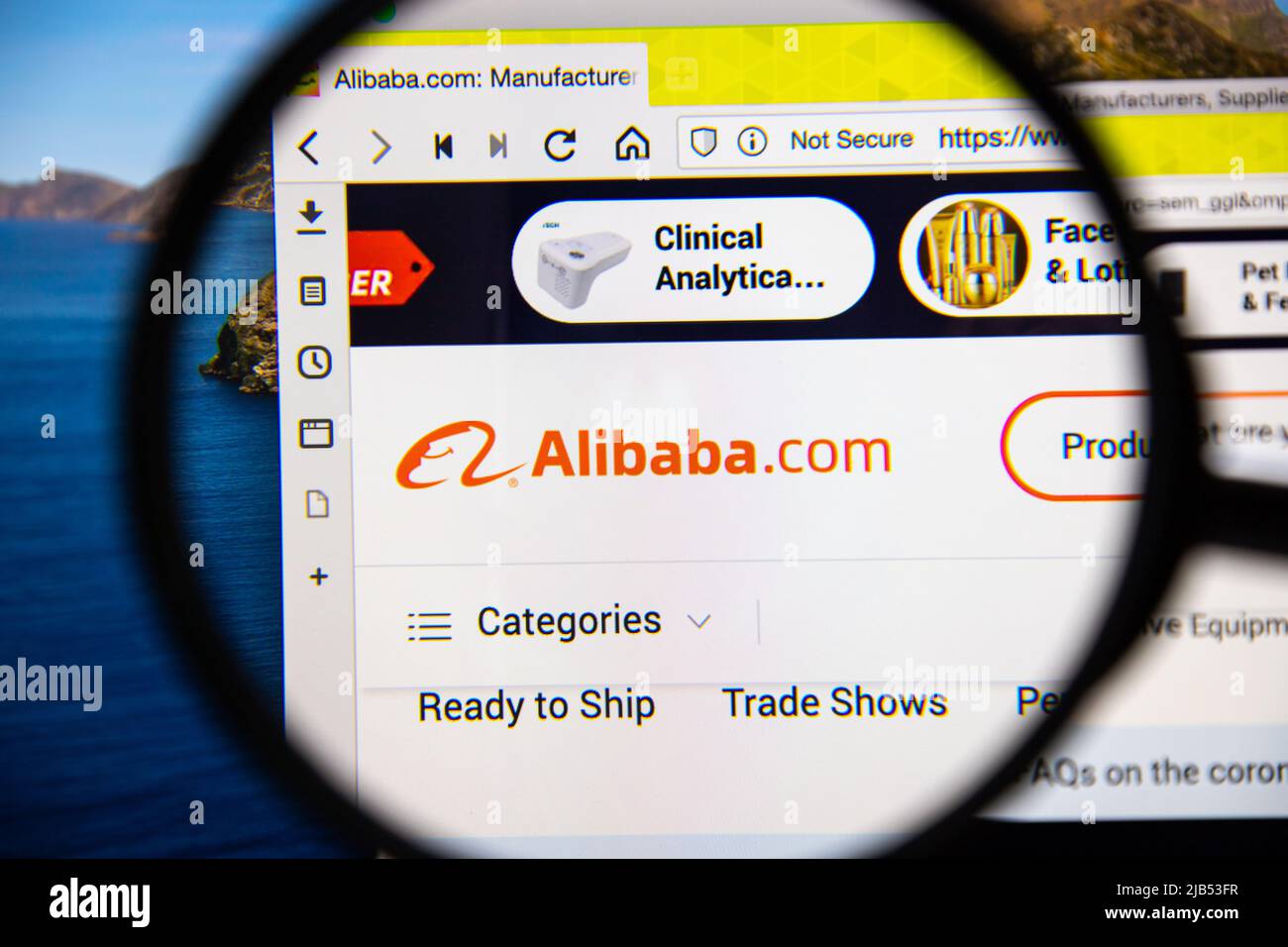 Alibaba logo on its website under magnifying glass. Alibaba Group is the world's largest retailer and e-commerce company Stock Photo