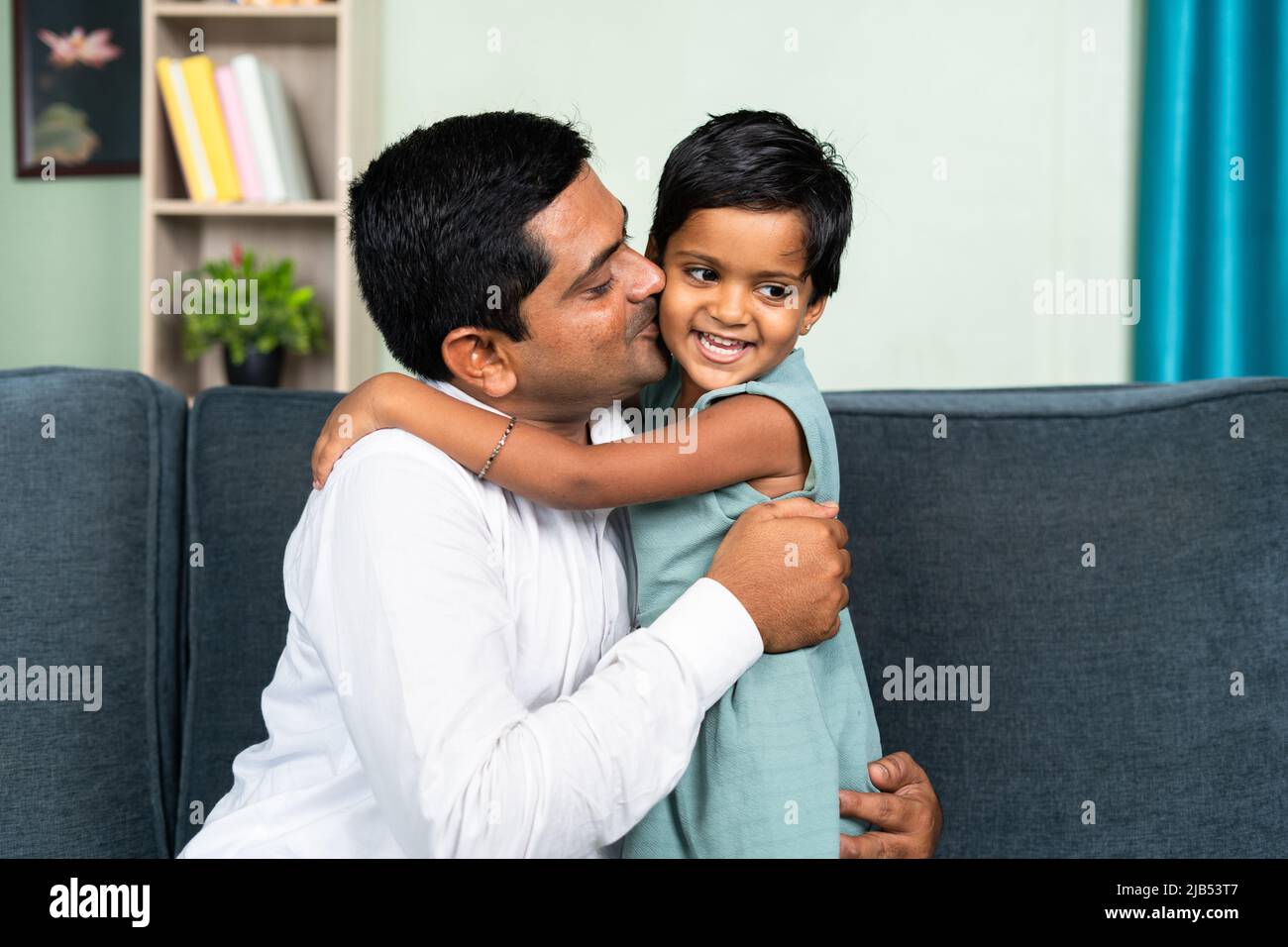 little toddler daughter hugging father by kissing at home - concept of love, parenthood and harmony Stock Photo