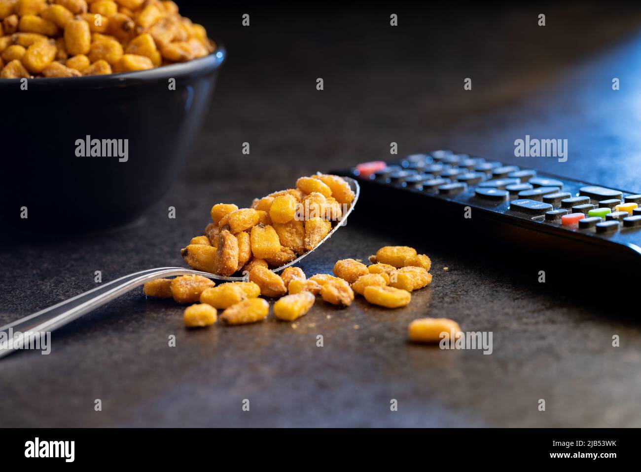 Roasted salted corn snack in spoon on a black table. Stock Photo