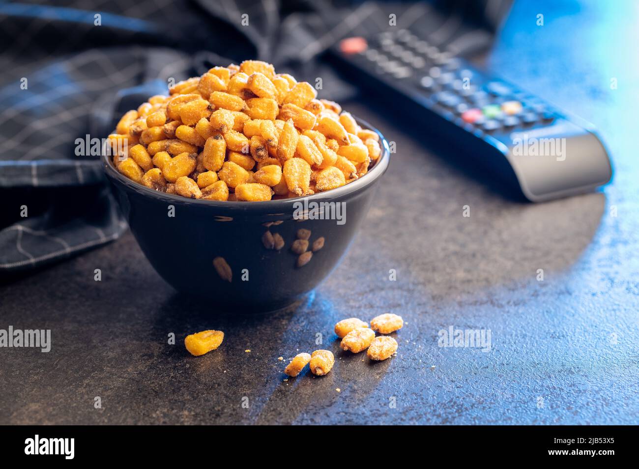 Roasted salted corn snack in bowl on a black table. Stock Photo