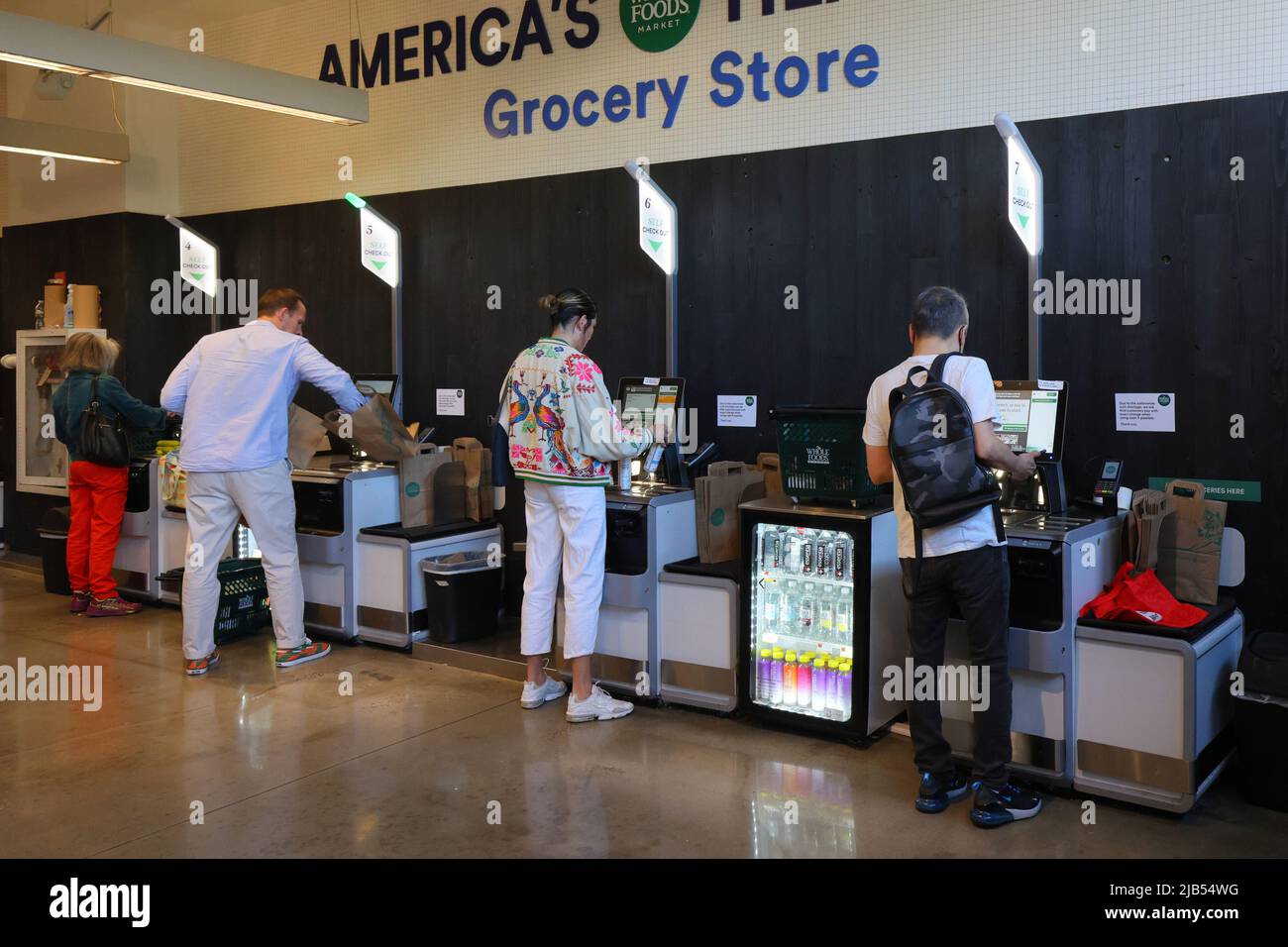 People scanning and bagging items at a self scan checkout kiosk in a supermarket. Grocery store automated retail machine in New York Stock Photo