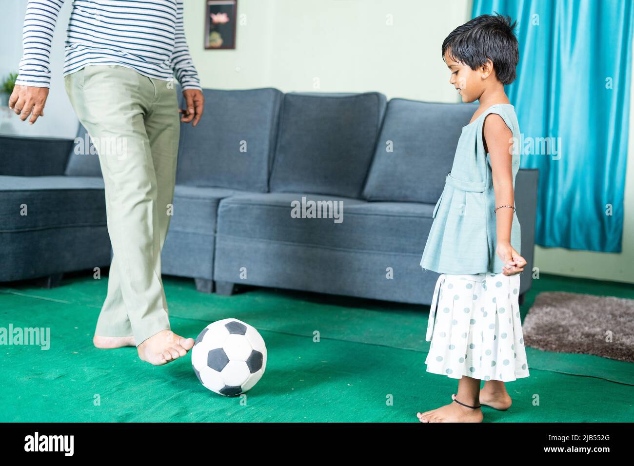 Father and lillte daughter playing football at home during weekend holidays - concept of family time, active and playful lifestyle Stock Photo