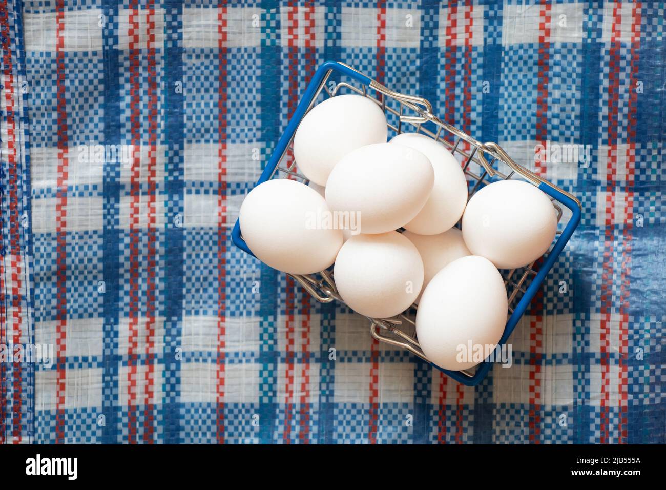White chicken eggs in a basket from a supermarket on a checkered client in the kitchen, eggs from a supermarket, food Stock Photo