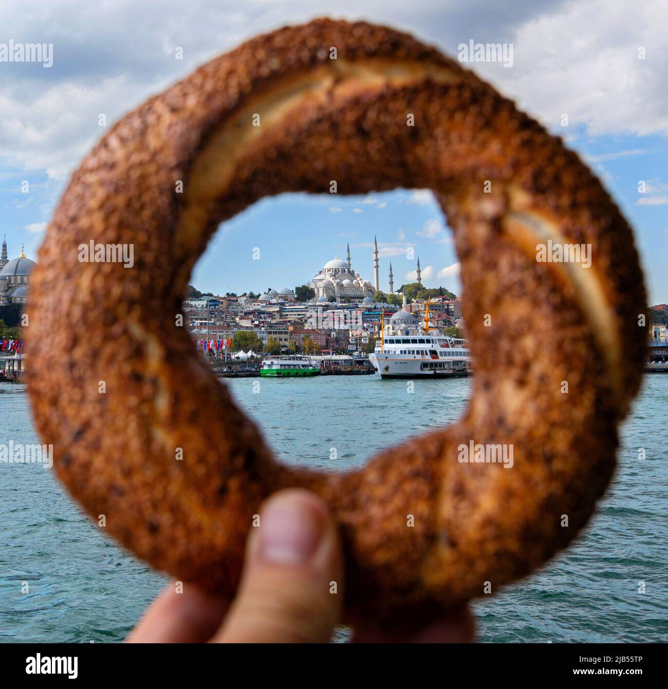 Traditional Turkish pastries Simit in hand. View of the old city of