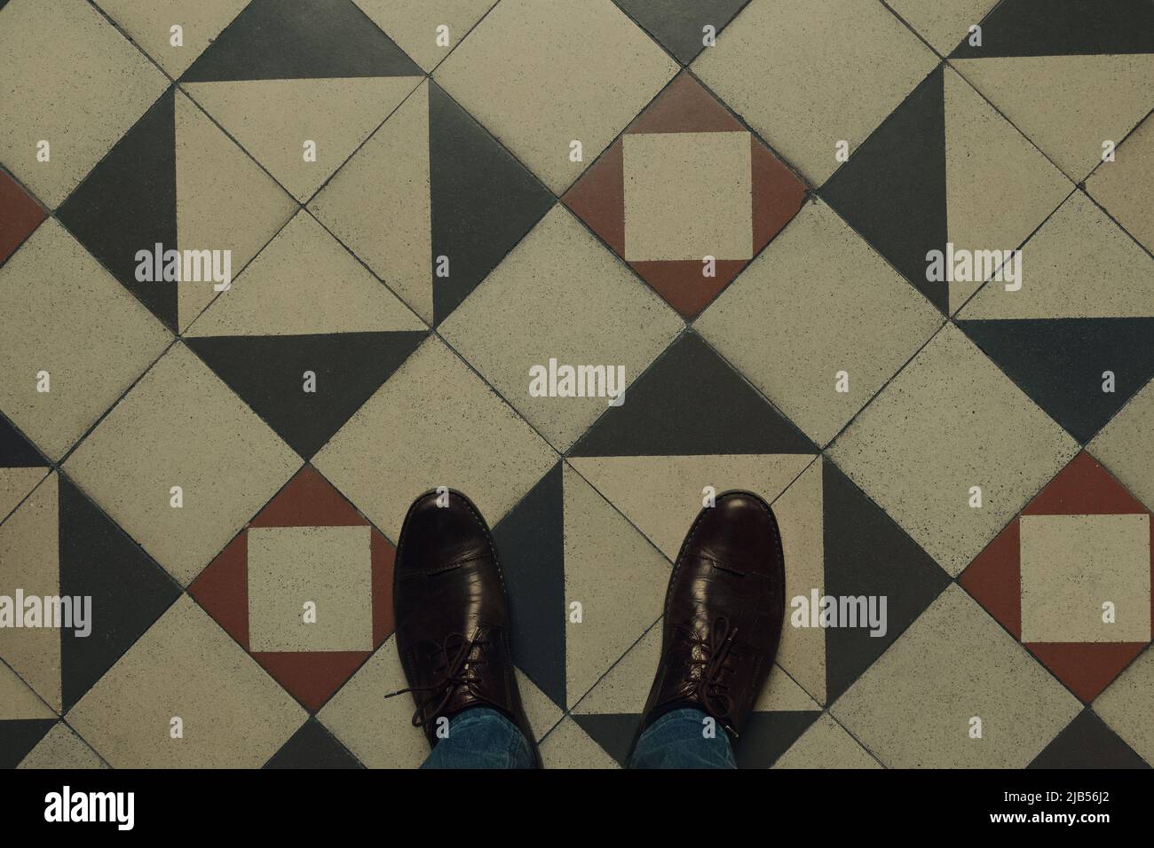 Standing on decorative hall floor, view from above on floor design and male shoes. Stock Photo