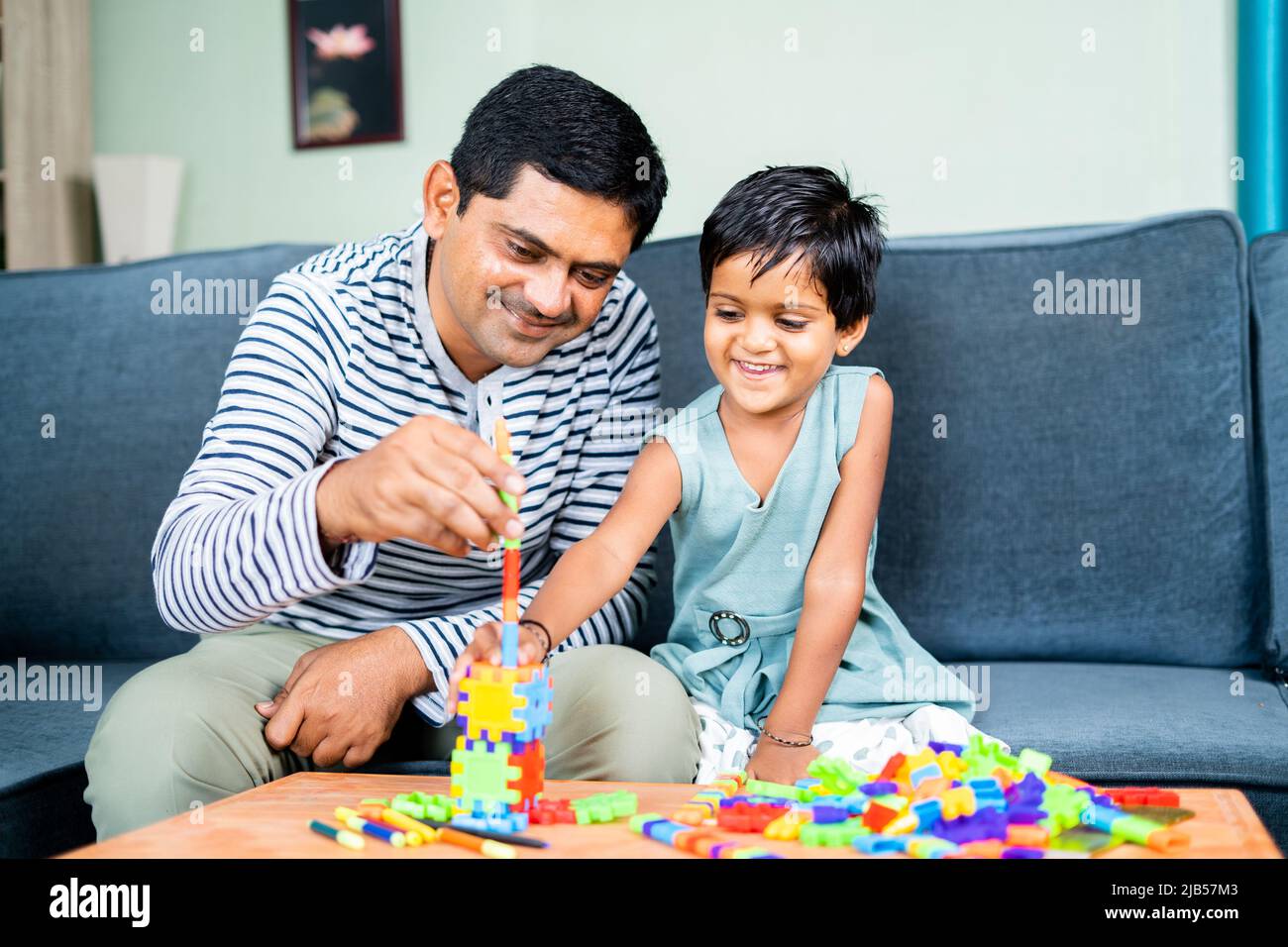 Father helping little daughter to make or build toy at home - concept of spending family time, childhood growth and development Stock Photo