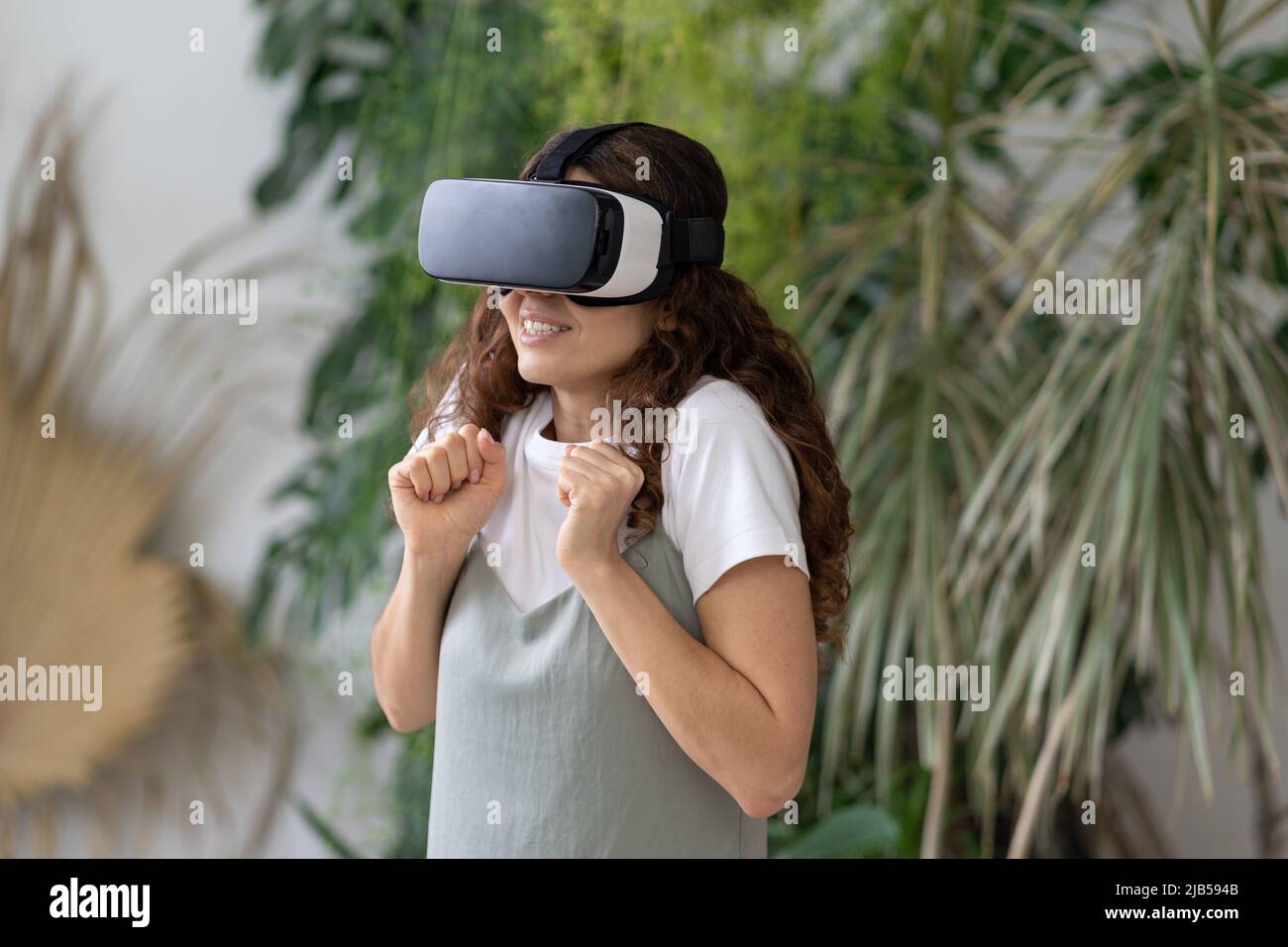 Emotional shocked woman in VR helmet using interactive technology for the first  time at home garden Stock Photo - Alamy