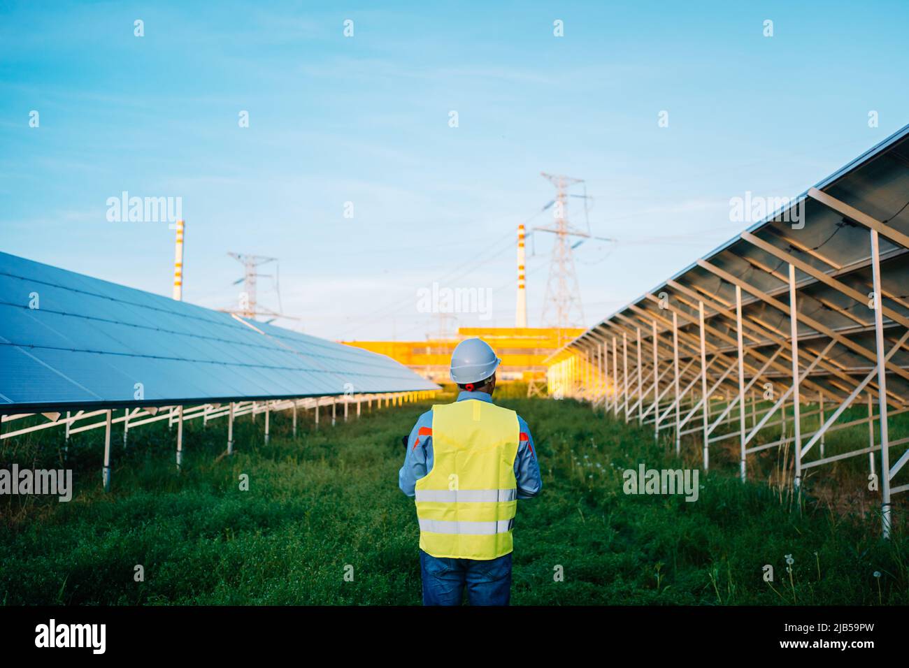 Rear view of worker at solar farm. Solar photovoltaic panels. Eco ...