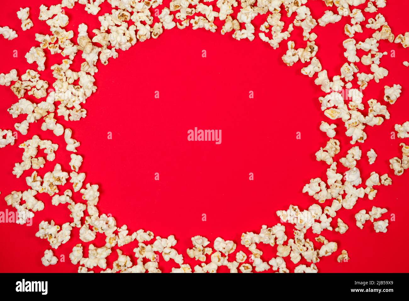 Popcorn on a red background, corn kernels top view. Stock Photo