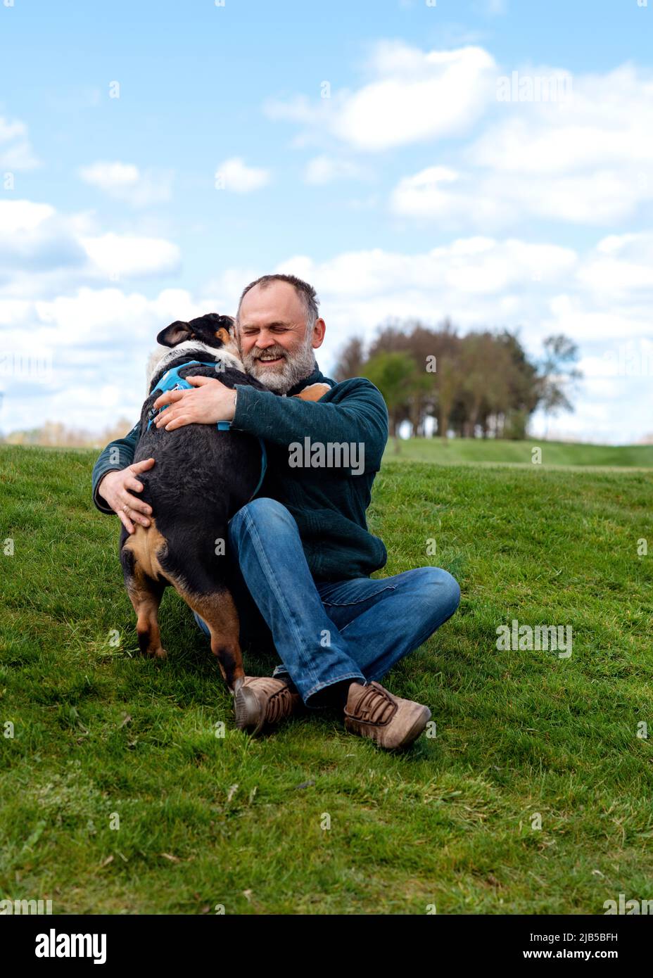 Man and English bulldog hugging in the park in sunny day in summe Stock Photo