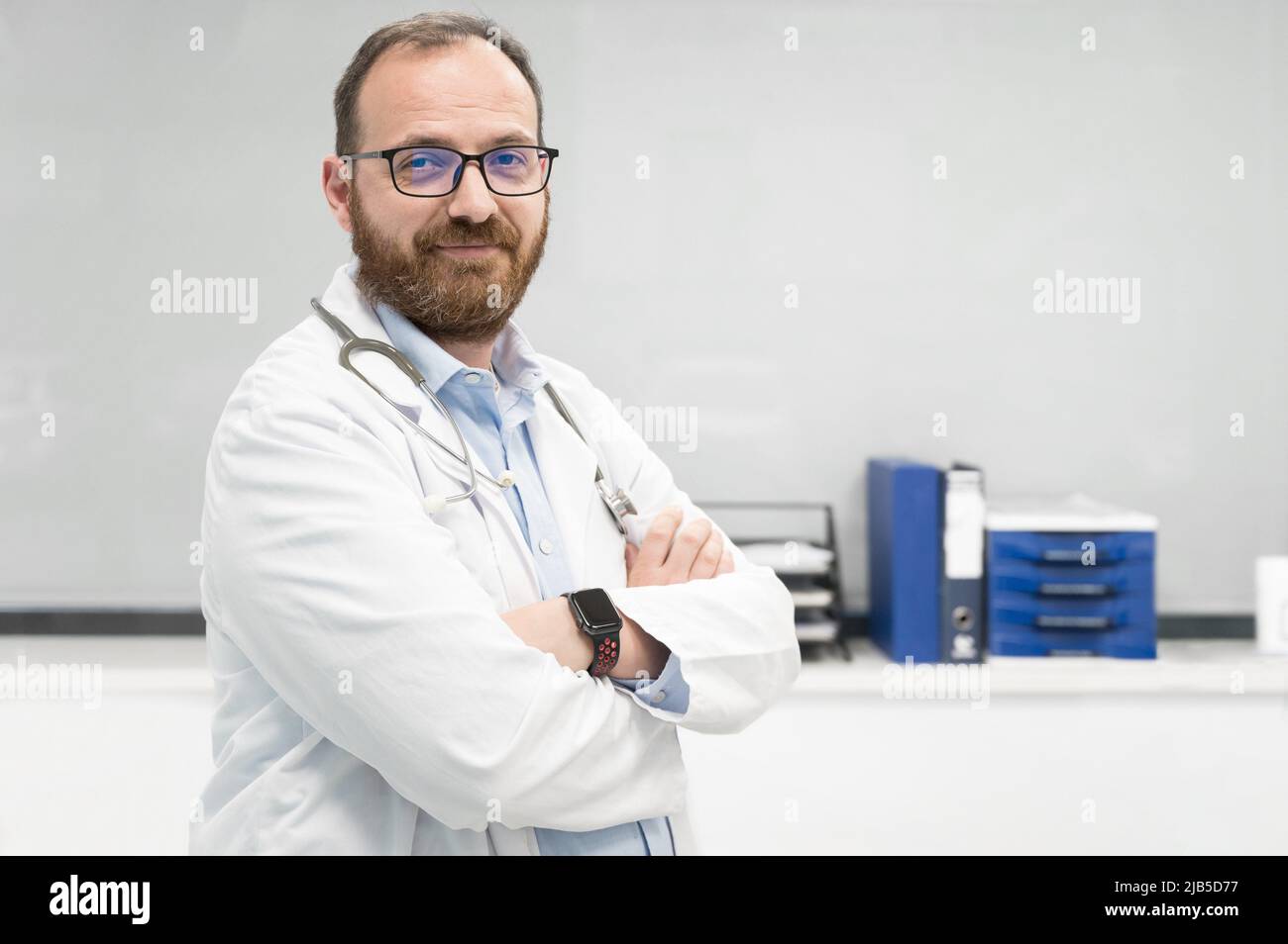Portrait of confident doctor crossing hands and smiling at camera. High quality photography. Stock Photo