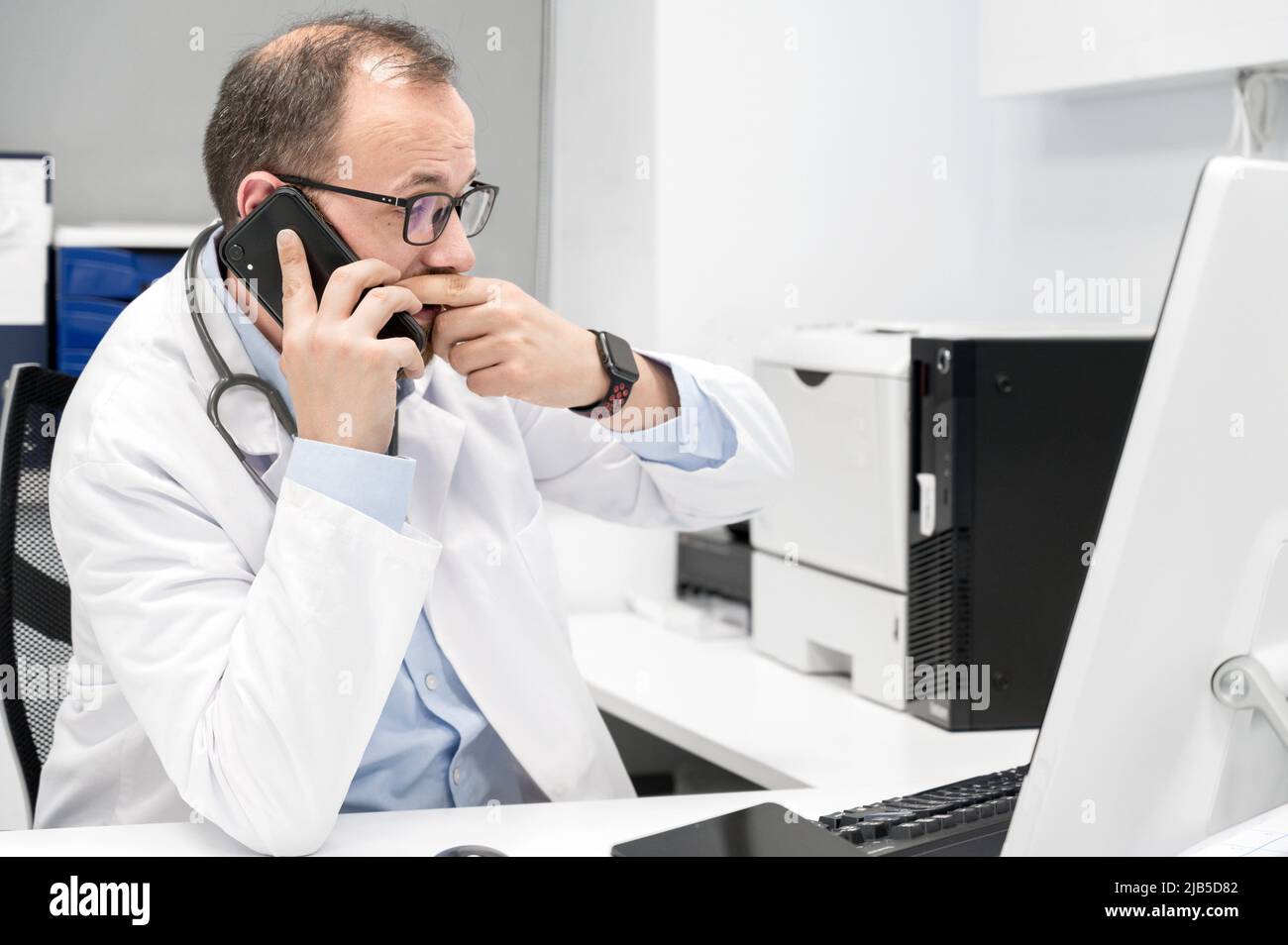 Doctor looking worried a desktop computer screen,, checking the results of a medical examination. High quality photography. Stock Photo