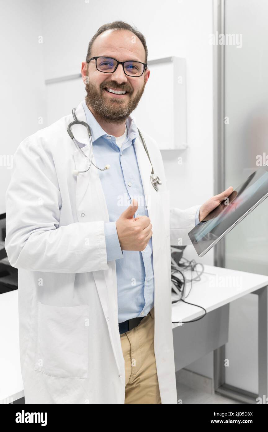 Friendly male doctor smiling and giving thumb up sign. High quality photo. Stock Photo