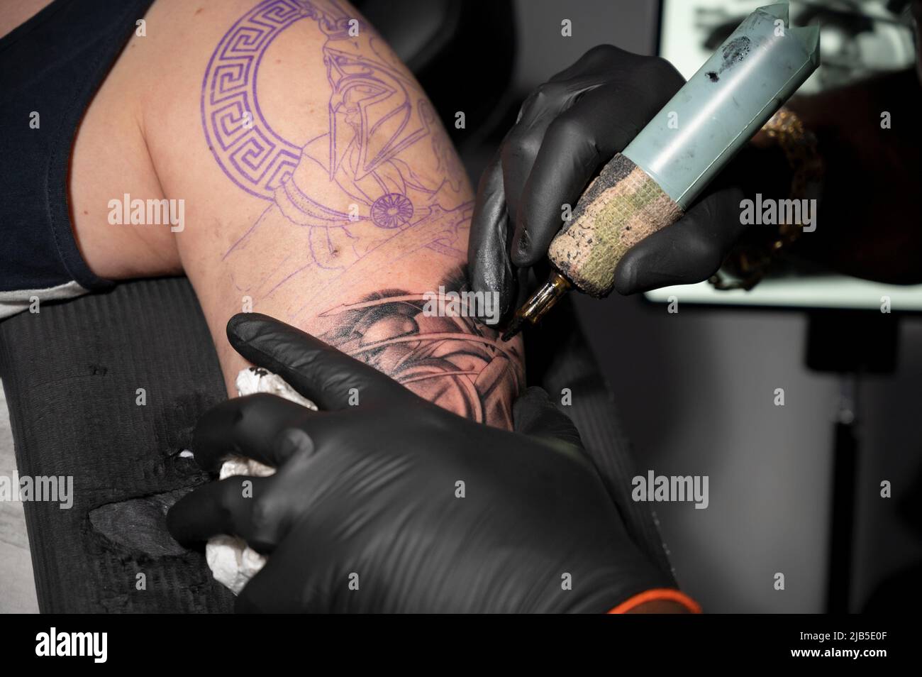 Close up macro view of tattooing process. Master makes contouring lines with his handmade professional liner machine. High quality photography. Stock Photo