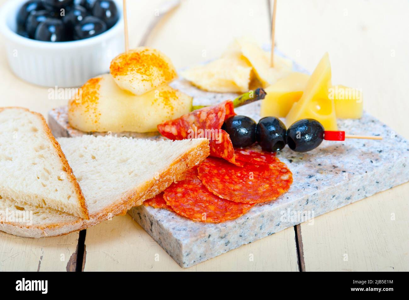 cold cut assortment cheese salami and fresh pears served on a granite stone. Stock Photo