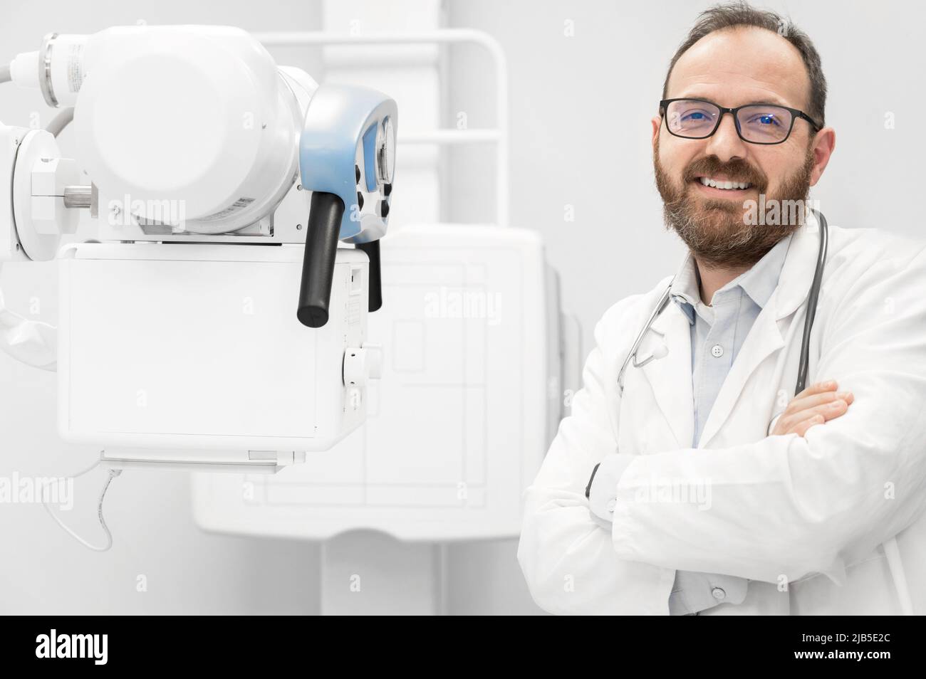 Smiling confident radiologist standing near x-ray equipment. High quality photo. Stock Photo