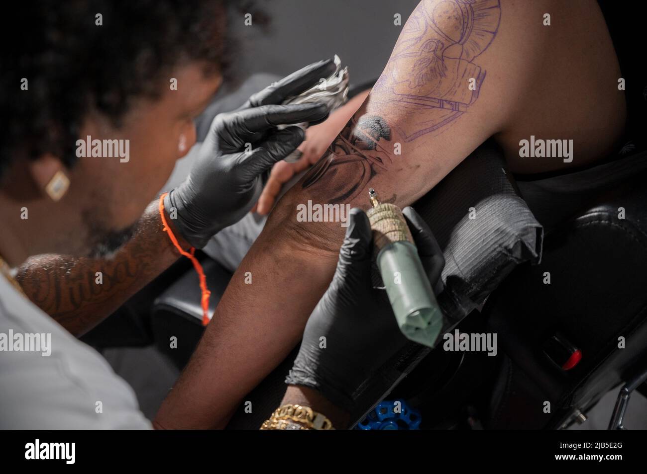 Cinematic shot of a Tattoo artist creating Body art at the tattoo studio. High quality photography. Stock Photo