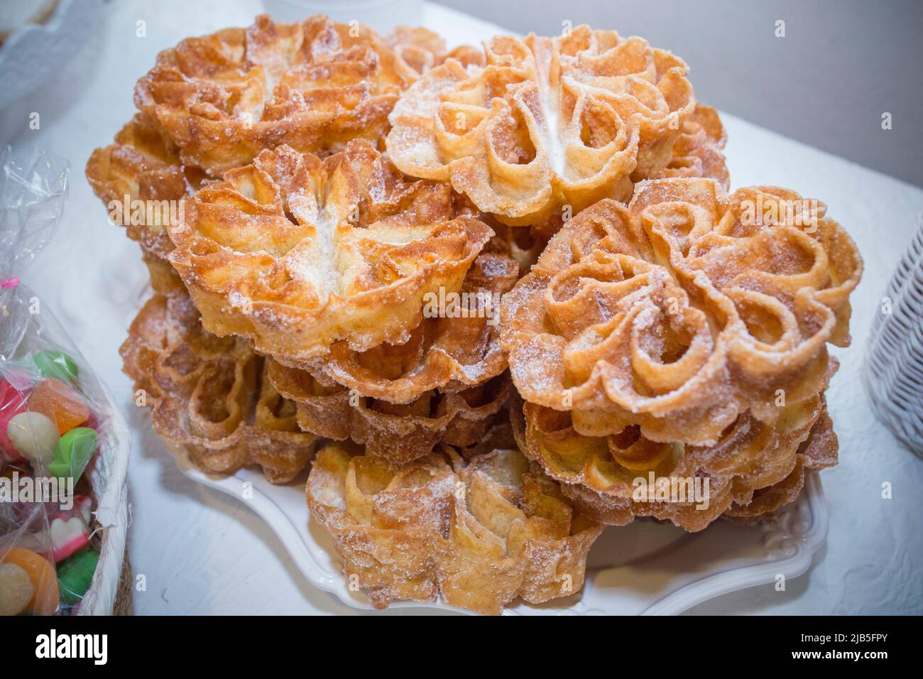Platter full of traditional fried flores or flowers. Spanish fritter dusted with sugar. Stock Photo