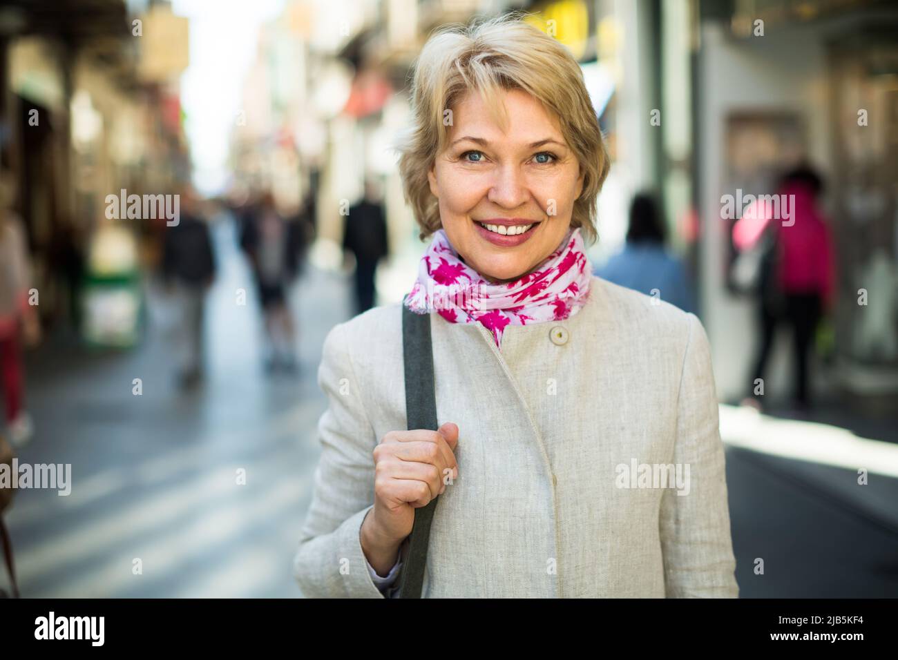Senior woman standing on street in town. Stock Photo