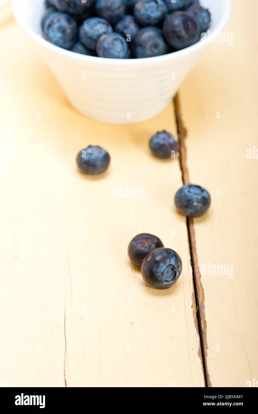 fresh blueberry on a bowl with silver spoon over wood table. Stock Photo
