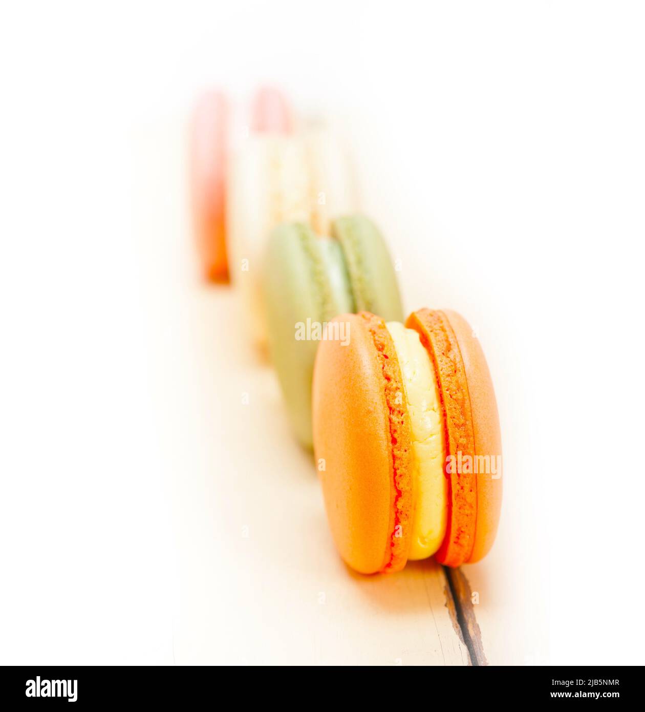 colorful french macaroons over a white rustic wood table. Stock Photo