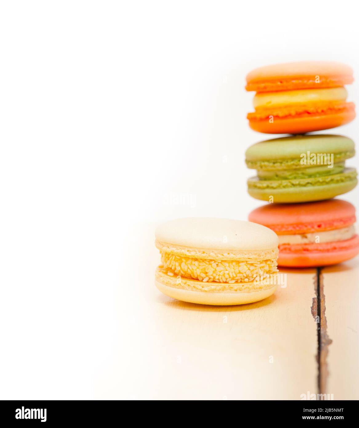 colorful french macaroons over a white rustic wood table. Stock Photo