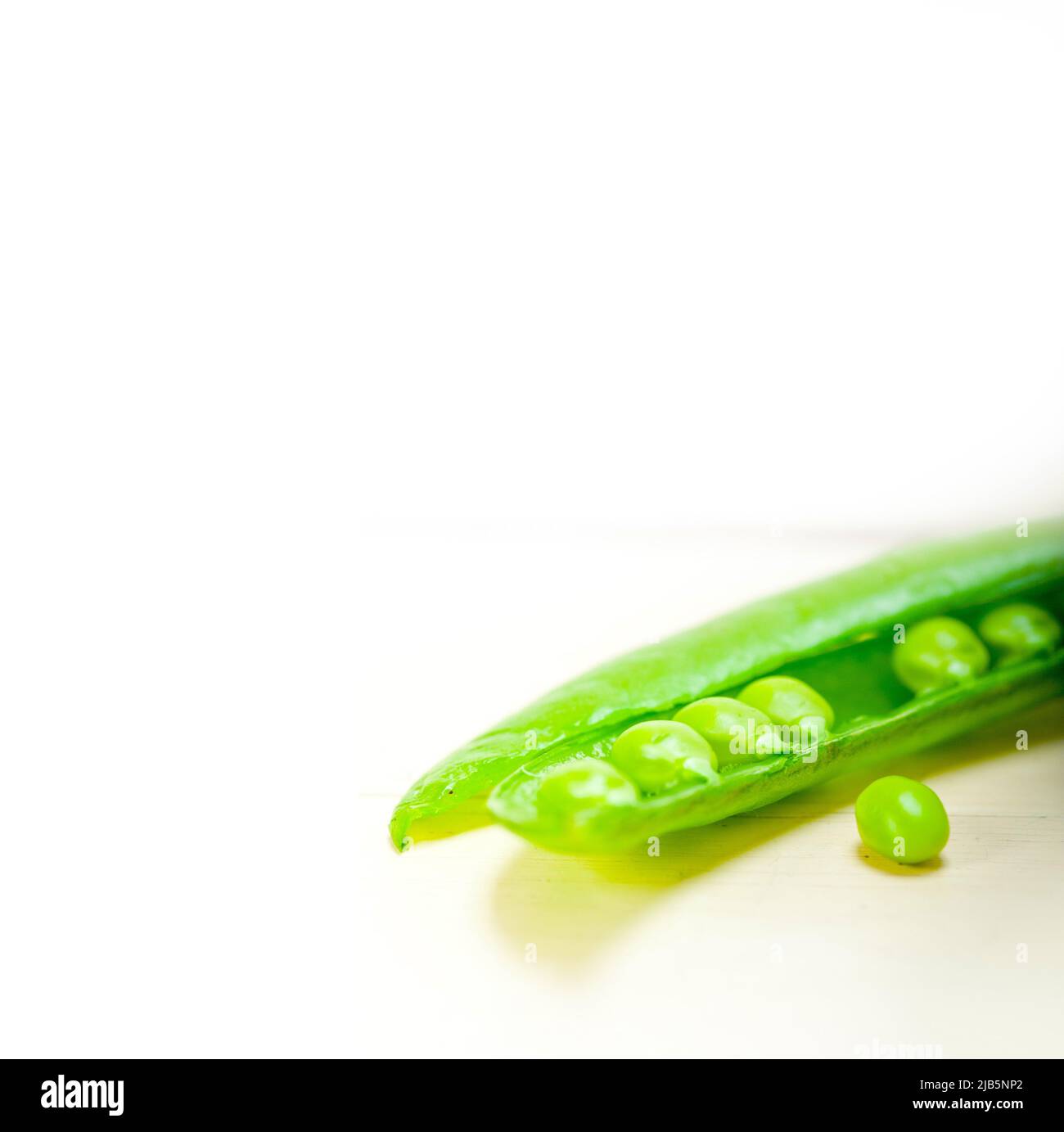 hearthy fresh green peas over a rustic wood table. Stock Photo