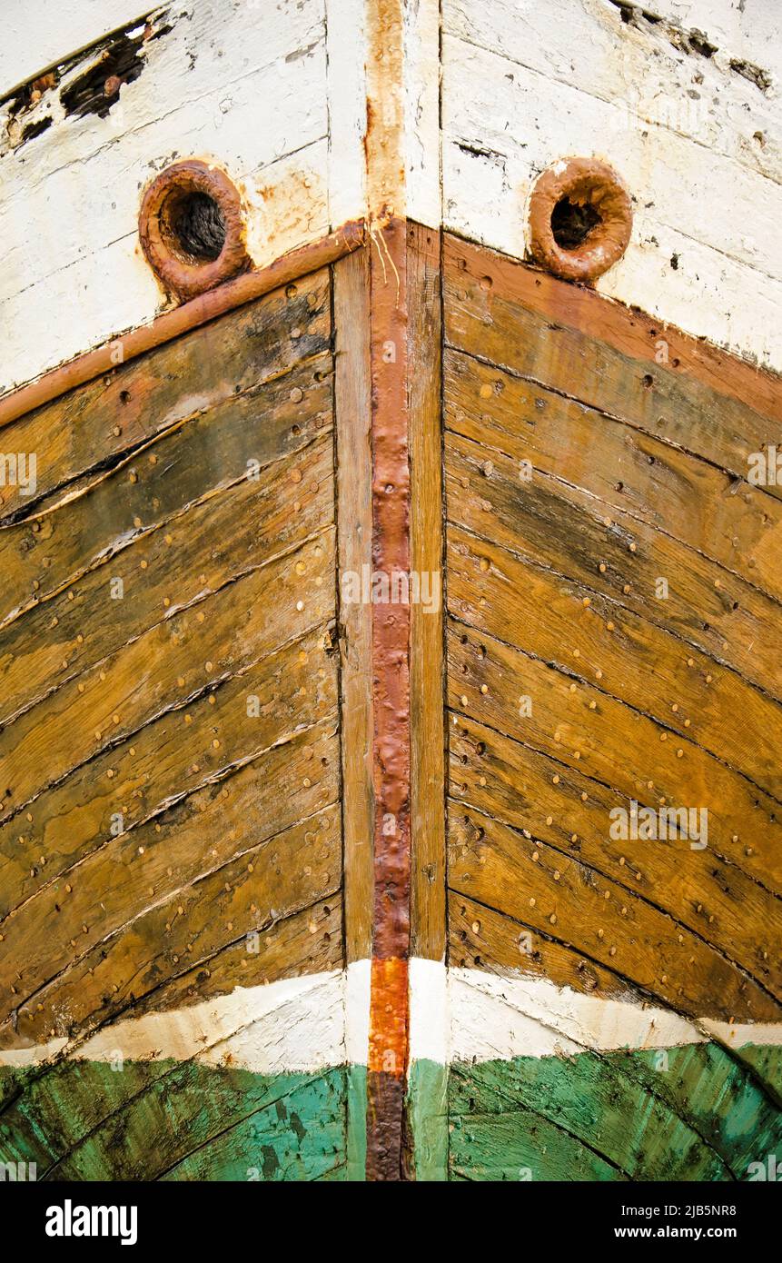 Front view of the bow of an old wooden boat, with rusty steel details, painted in bright but ...
