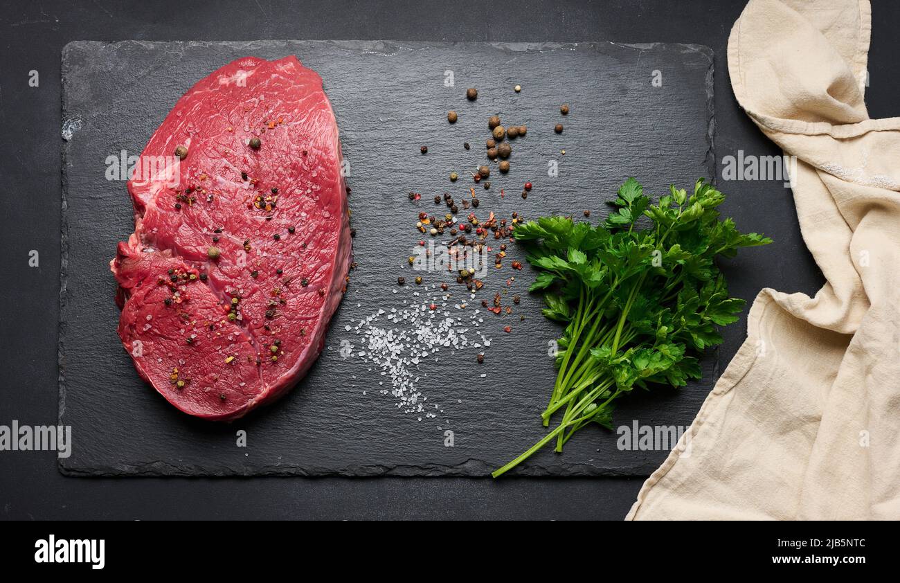 Raw beef tenderloin lies on a cutting board and spices for cooking on a