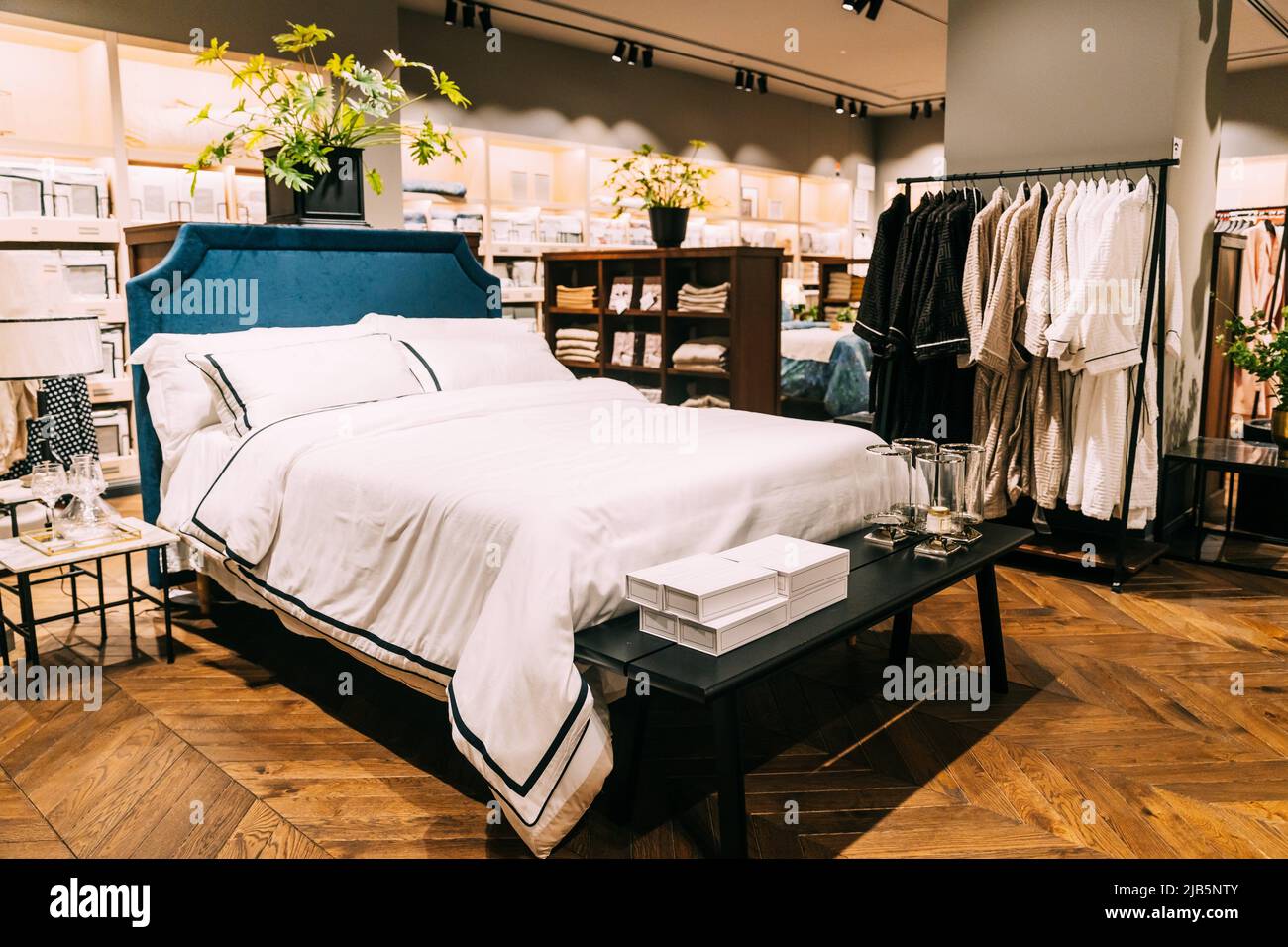 View of assortment of decor for interior shop in store of shopping center. View of bed with linen, bed linen, pillows, plaid. View of home Stock Photo
