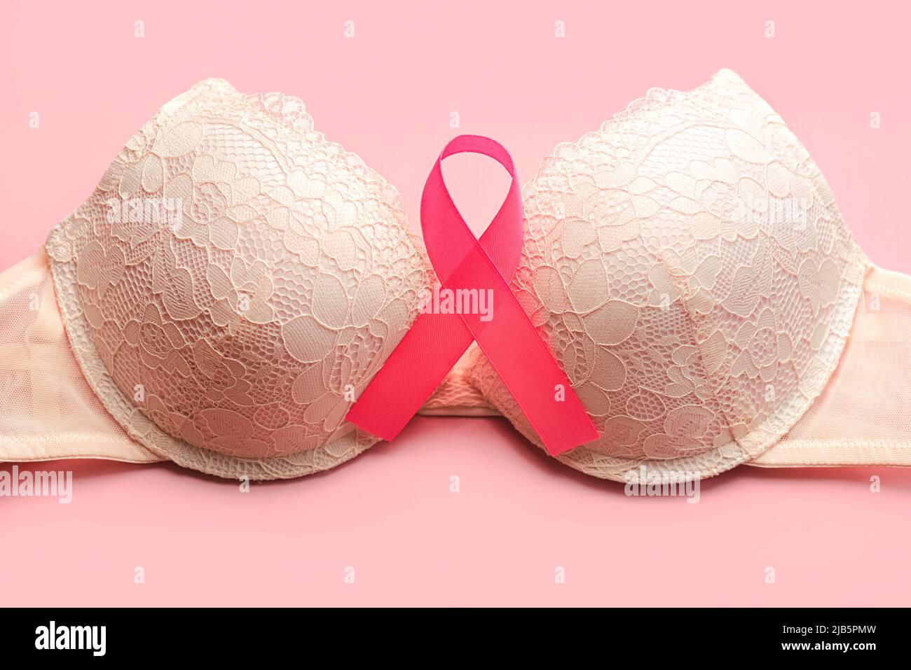 Breast cancer concept. Top view of Women's bra and pink ribbon symbol breast cancer awareness over pink background Stock Photo