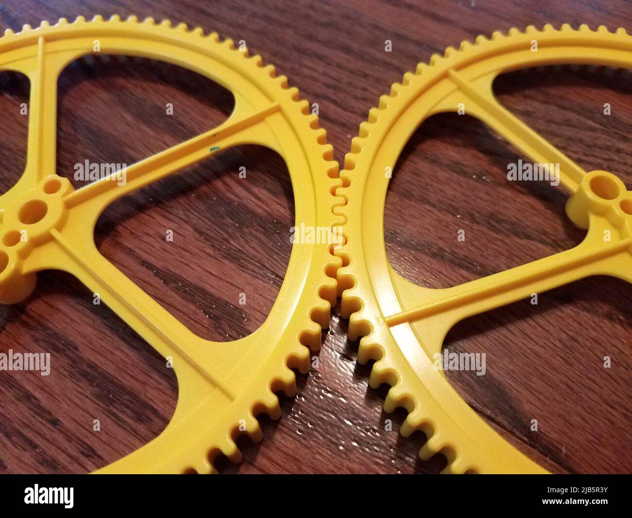 two large yellow plastic gears on brown wood floor Stock Photo Alamy