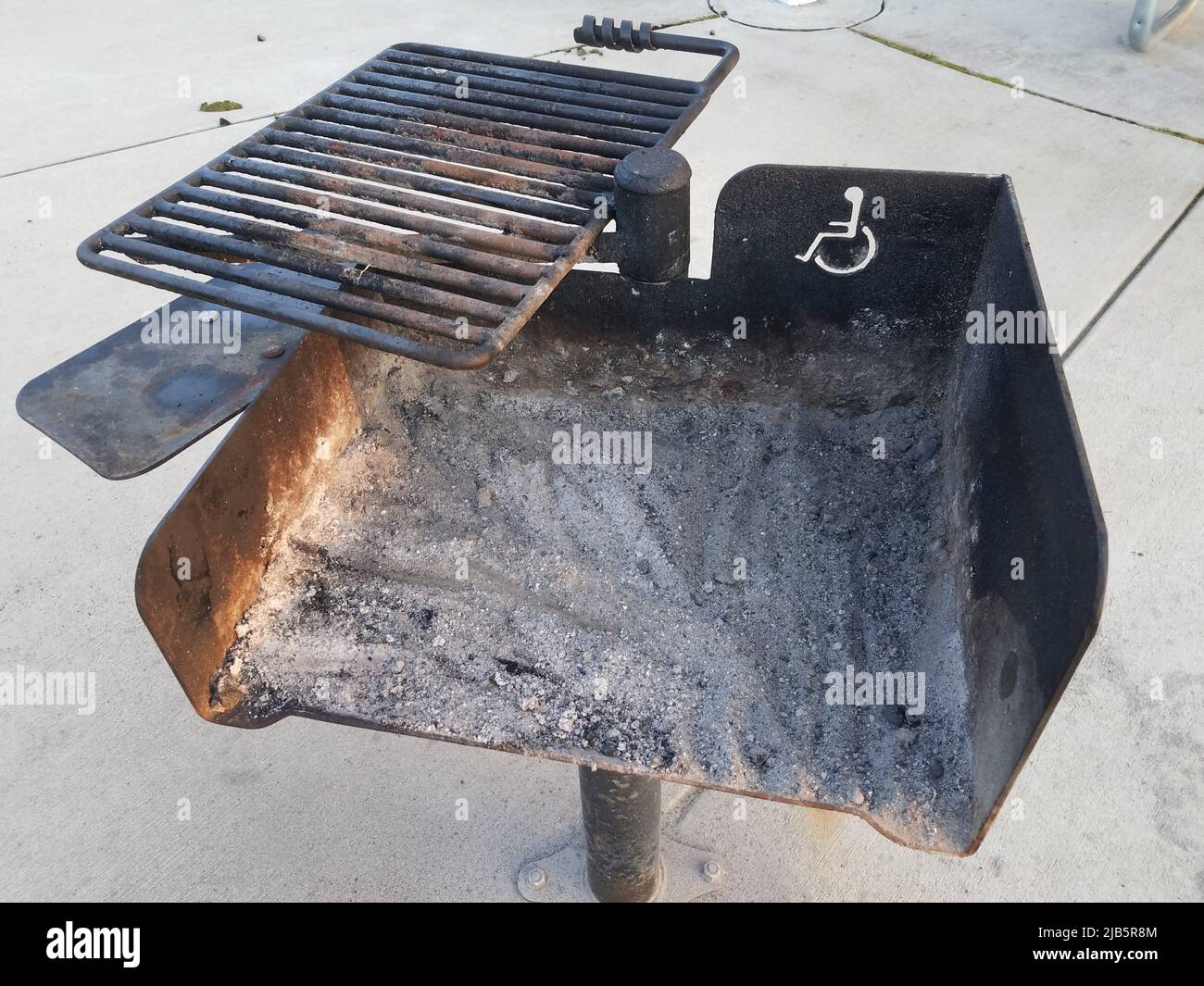 a dirty grill on cement with handicap or wheelchair symbol. Stock Photo