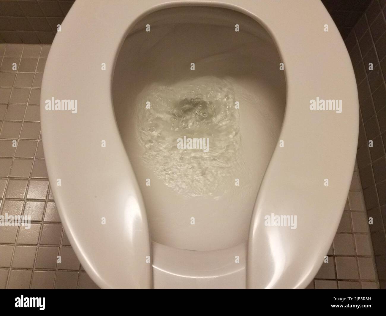 white toilet with water being flushed in bathroom Stock Photo Alamy