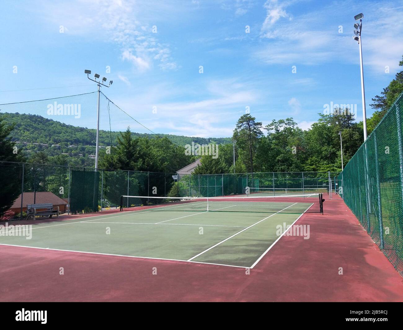 green and red tennis court with fence and lights Stock Photo - Alamy