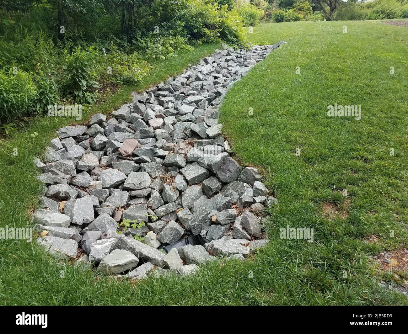 green grass lawn or yard with large grey rocks. Stock Photo