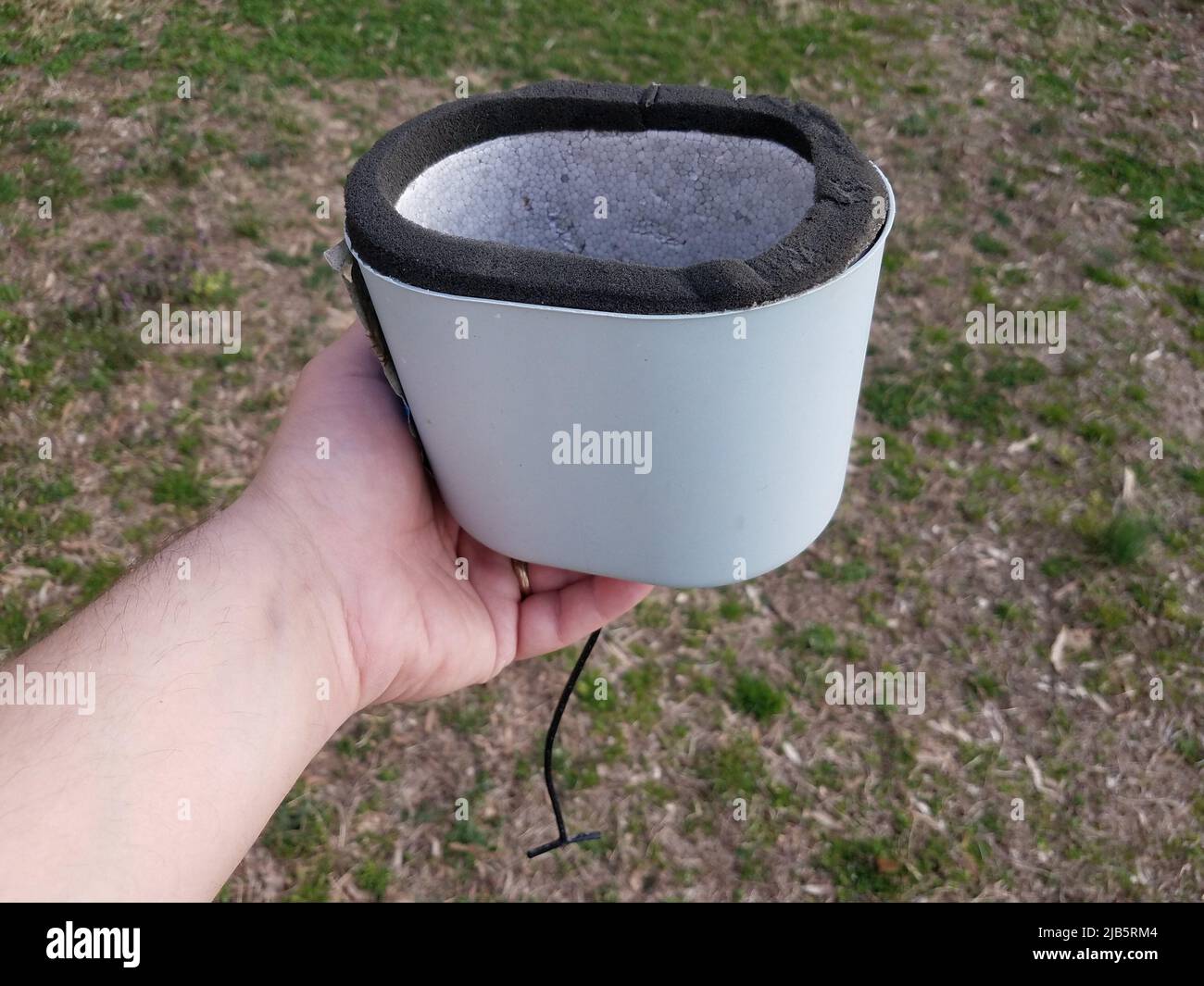 hand holding water spigot insulation cap or cover over grass or lawn