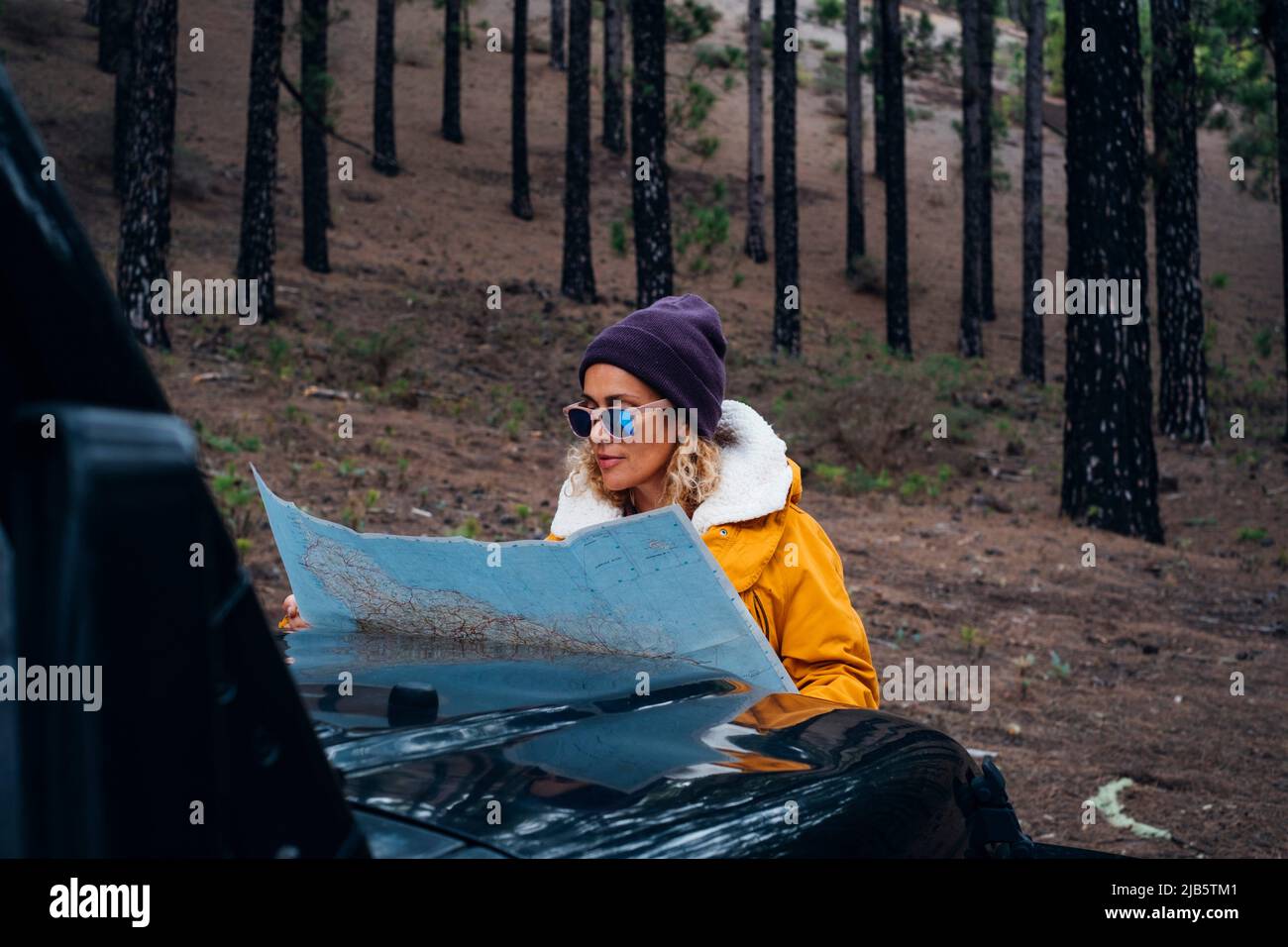 Portrait of beautiful woman travel alone in the woods outdoor forest park with vehicle - female people and adventure lifestyle - young lady check map Stock Photo