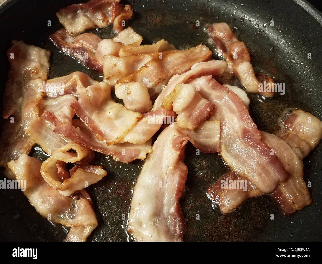 Frying pan with cooked bacon rashers on white background Stock Photo - Alamy