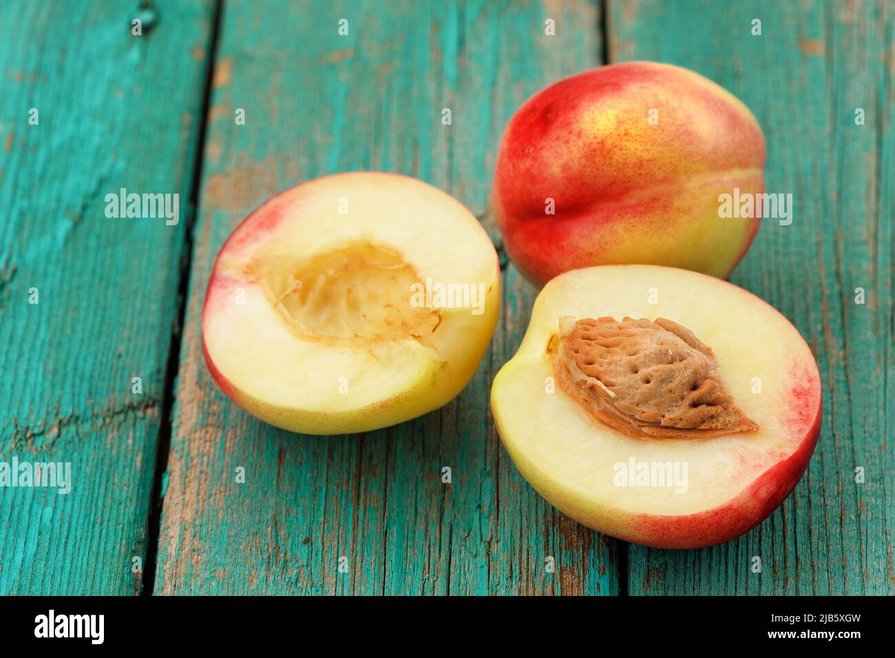Two fresh nectarines, whole and split with stone, on vintage turquoise