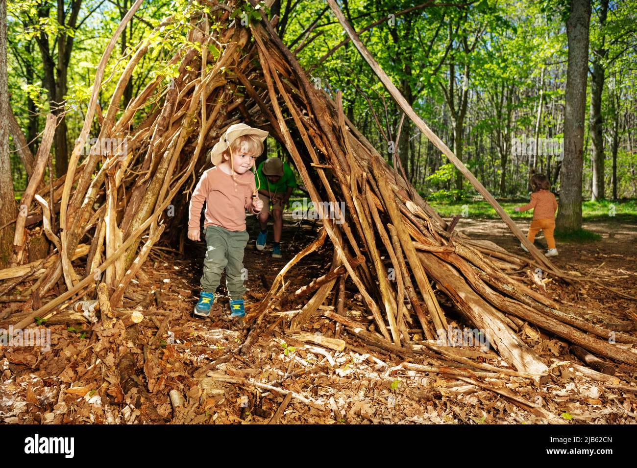 Boy with boy-scout hat plain in the forest hut of branches Stock Photo