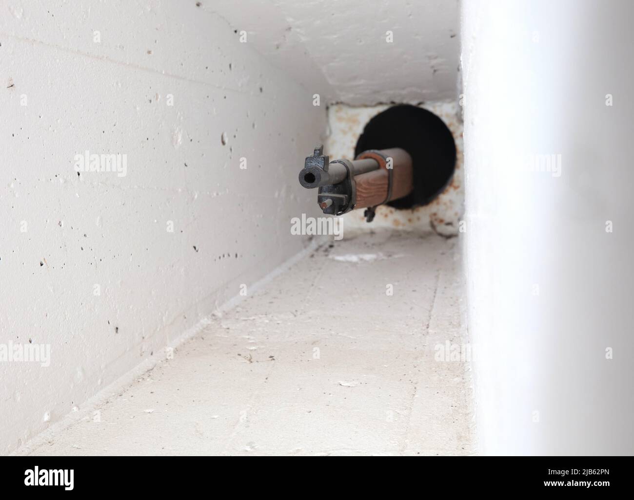 Small hole with a gun sticking out of it at the entrance of an old WW2
