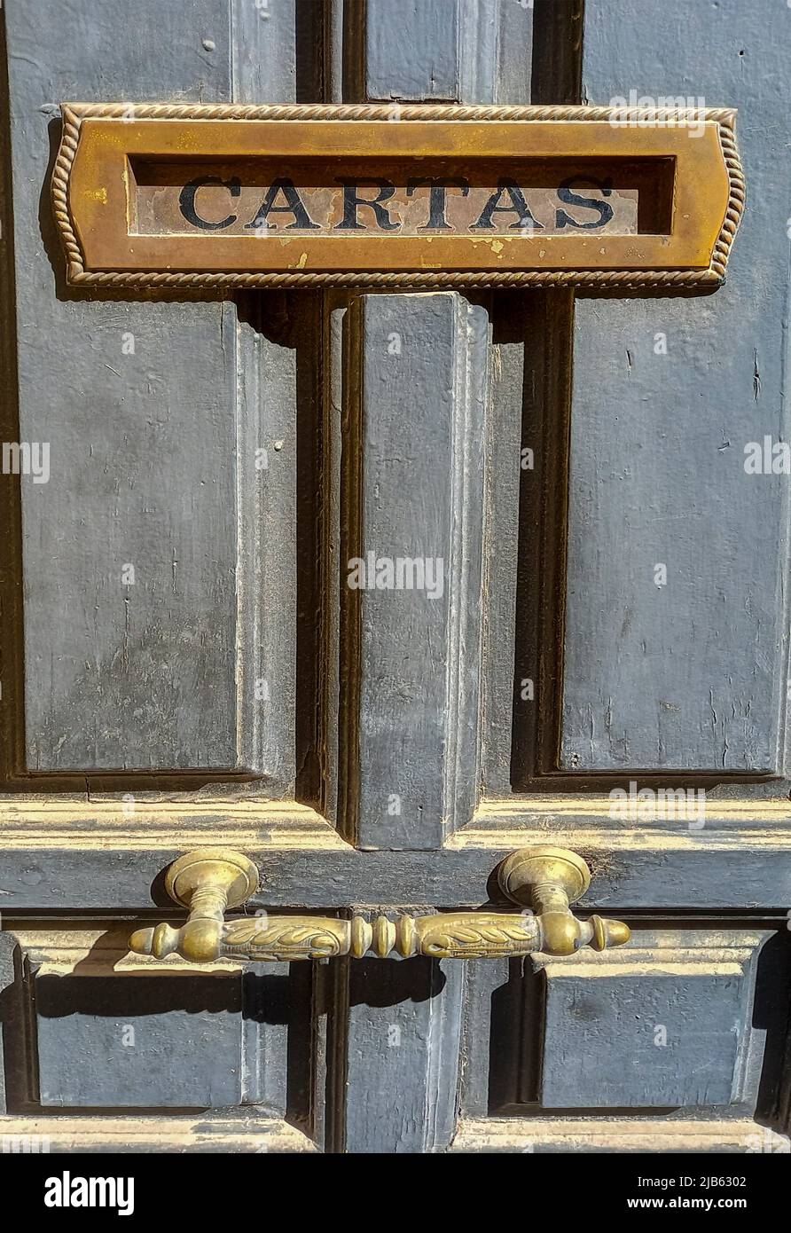 Built-in letter box on dusty old wooden door. Spanish caption, Selective focus. Stock Photo