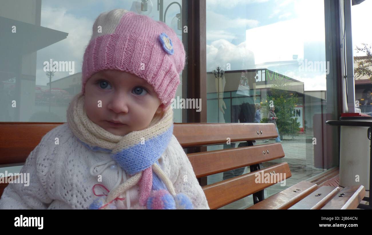 Colorfully dressed girl with blue eyes and colorful handmade hat sits ...