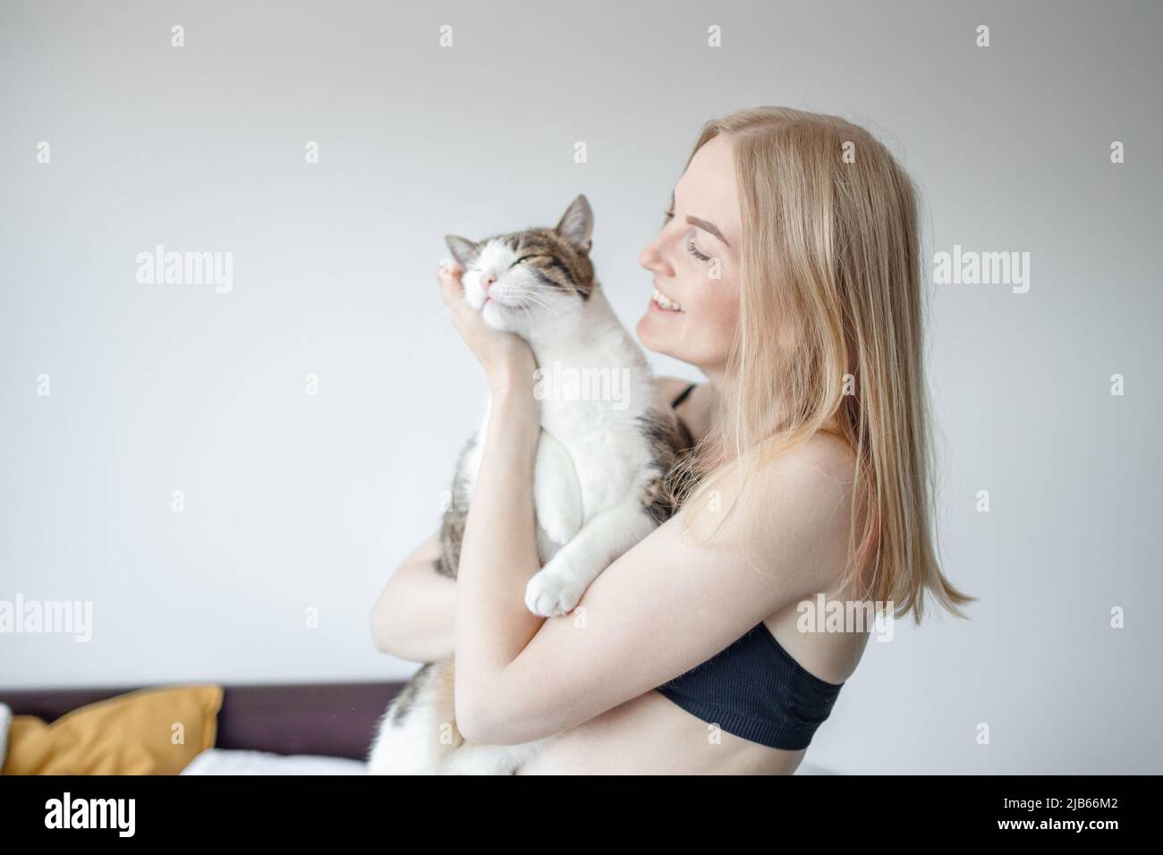 Blond girl sitting and holding a young cat available as Framed