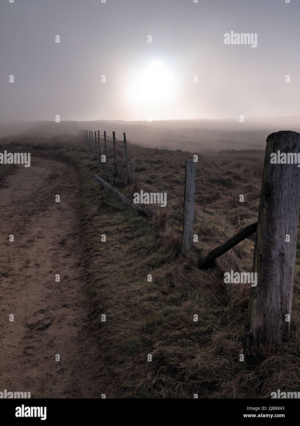Fence line along old the turnpike in fog near the Penine Way at Standedge near Diggle. Stock Photo