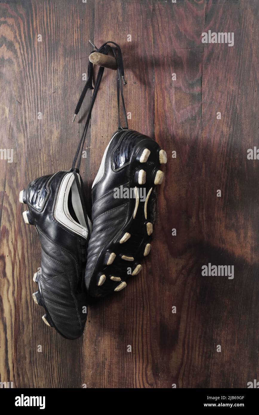 A pair of soccer boots hanging on a wooden wall. The end of the