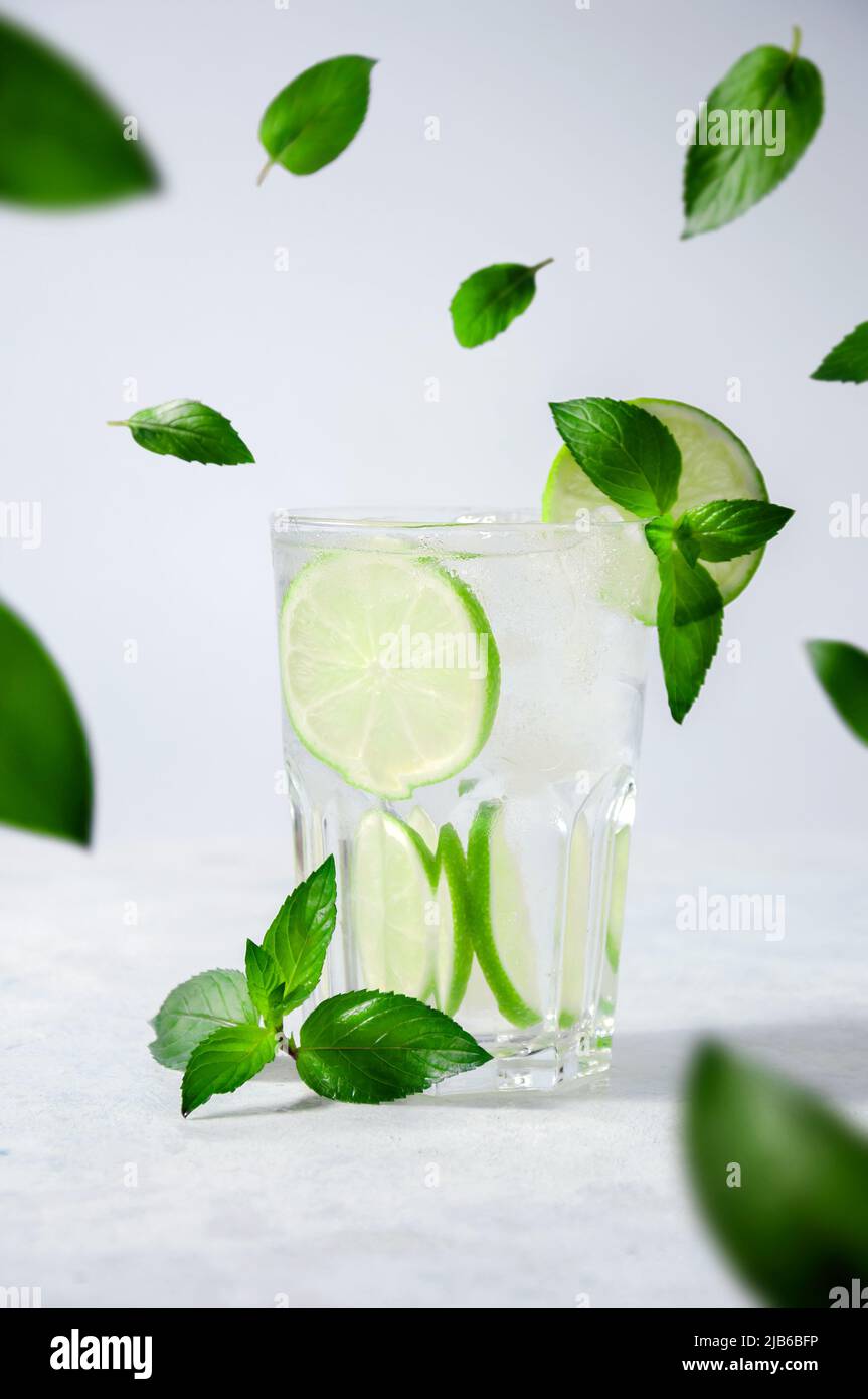 Cocktail Mojito or Lemonade with Lime, Mint and Ice on Light Background. Concept Fresh Summer Drinks Stock Photo